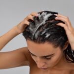 Shampoo massage creates dense foam across crown of wet brunette hair